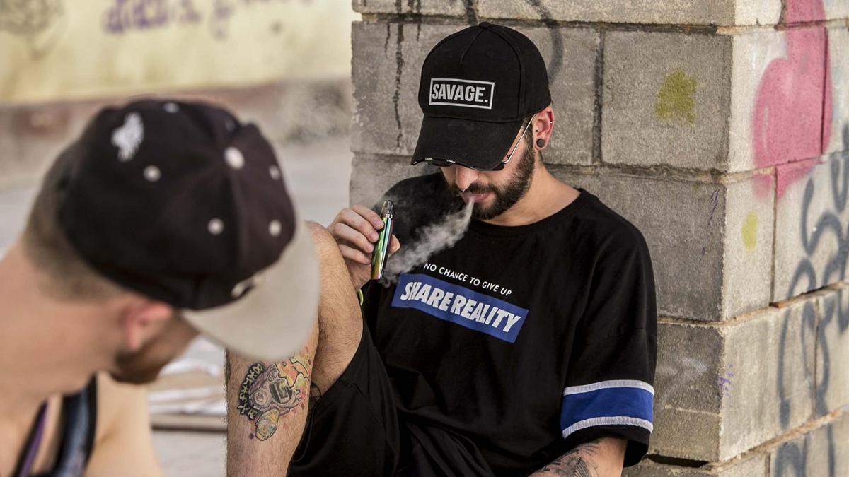 Un joven vapea con un cigarrillo electrónico