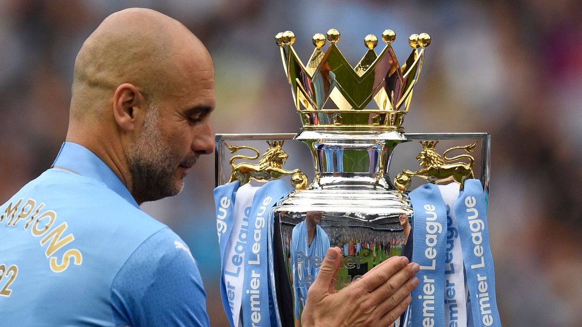 Manchester City's Spanish manager Pep Guardiola caresses the Premier League trophy as he prepares to celebrate their title during the award ceremony after the English Premier League football match between Manchester City and Aston Villa at the Etihad Stadium in Manchester, north west England, on May 22, 2022. (Photo by Oli SCARFF / AFP) / RESTRICTED TO EDITORIAL USE. No use with unauthorized audio, video, data, fixture lists, club/league logos or 'live' services. Online in-match use limited to 120 images. An additional 40 images may be used in extra time. No video emulation. Social media in-match use limited to 120 images. An additional 40 images may be used in extra time. No use in betting publications, games or single club/league/player publications. /