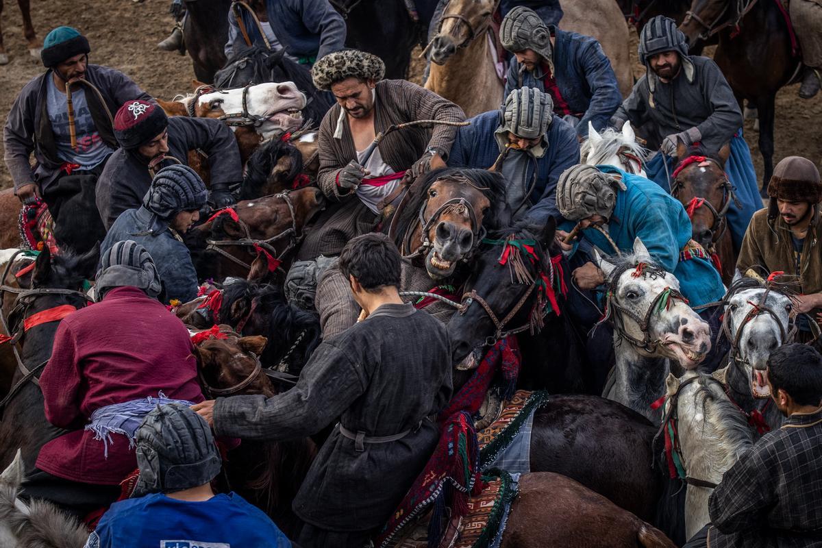 Jinetes afganos compiten en un deporte tradicional de Asia Central, en el que los jugadores montados a caballo intentan colocar una bolsa que se asemeja a un cadáver de cabra en una portería