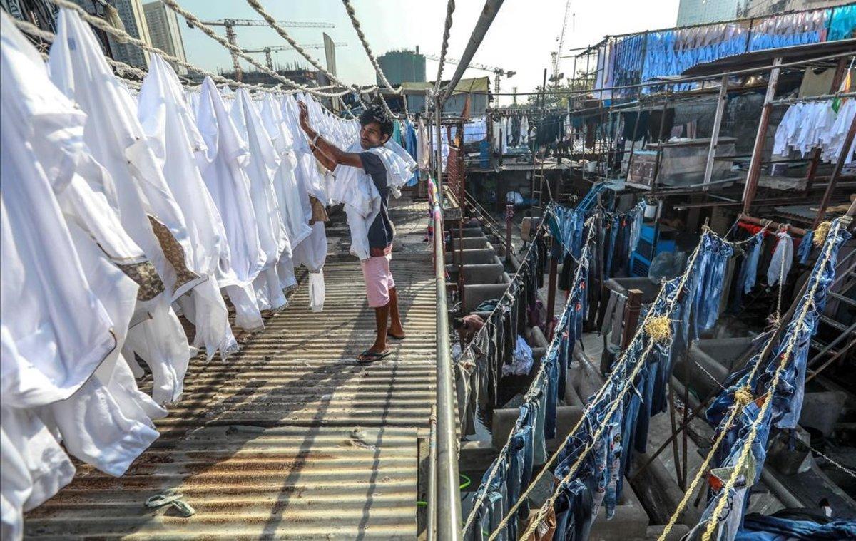 Un lavandero tiende camisas y otras prendas para que se sequen al aire libre en la popular lavandería de Dhobi Ghat, en Bombay, India.