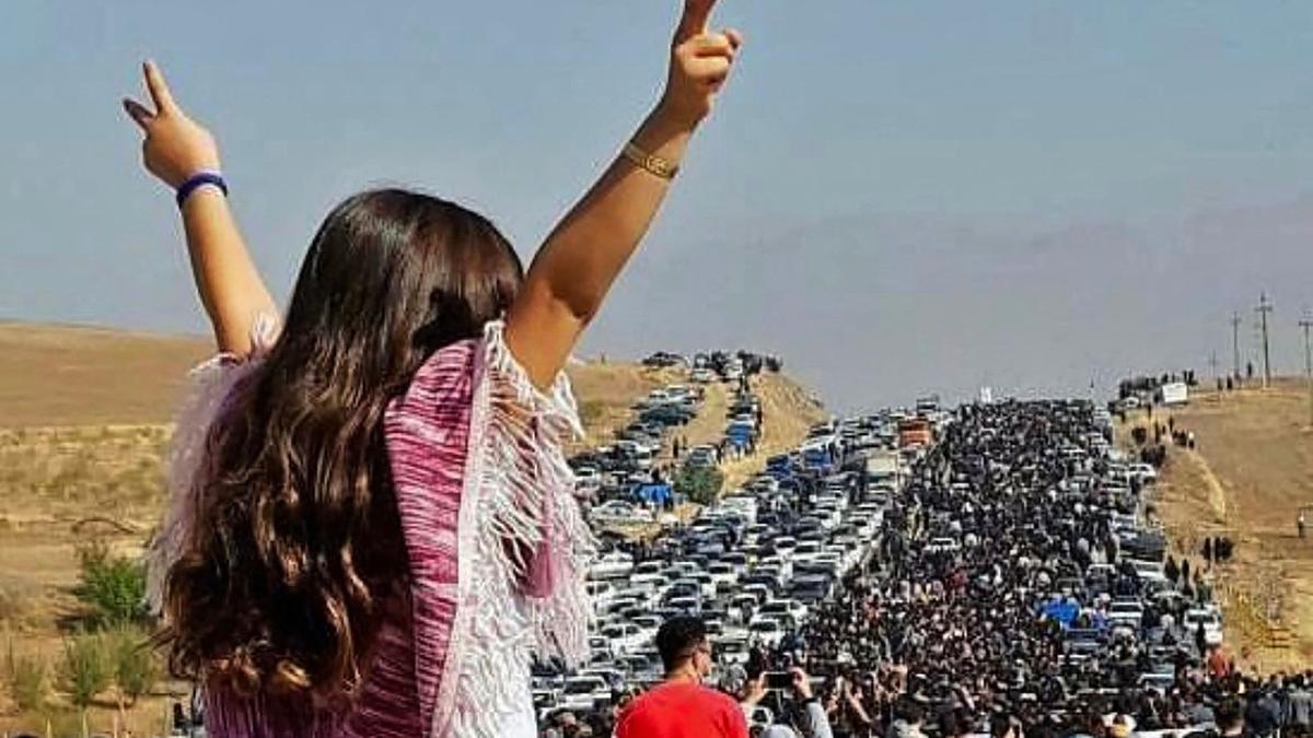 Una mujer sin velo en la parte superior de un vehículo mientras miles de personas se dirigen hacia el cementerio de Aichi en Saqez, la ciudad natal de Mahsa Amini en la provincia occidental iraní de Kurdistán, para conmemorar los 40 días desde su muerte.