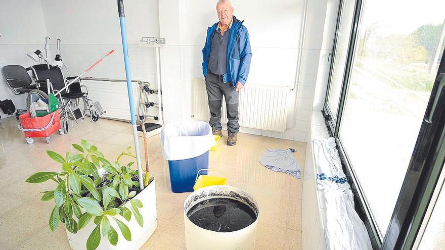 Aurelio Fernández, junto a los cubos donde se recoge el agua de las goteras, en la sala encharcada.