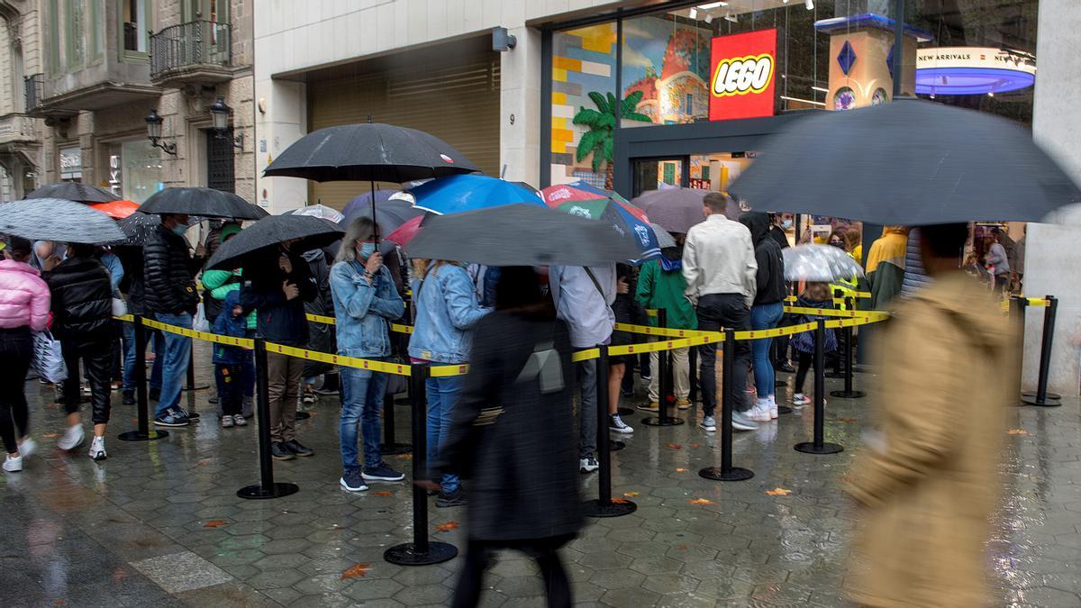 Barcelona. 30.10.2021. Barcelona Colas de acceso bajo la lluvia para acceder a la nueva tienda Lego en el número 9 del Paseo de Gracia de Barcelona. Fotografía de Jordi Cotrina