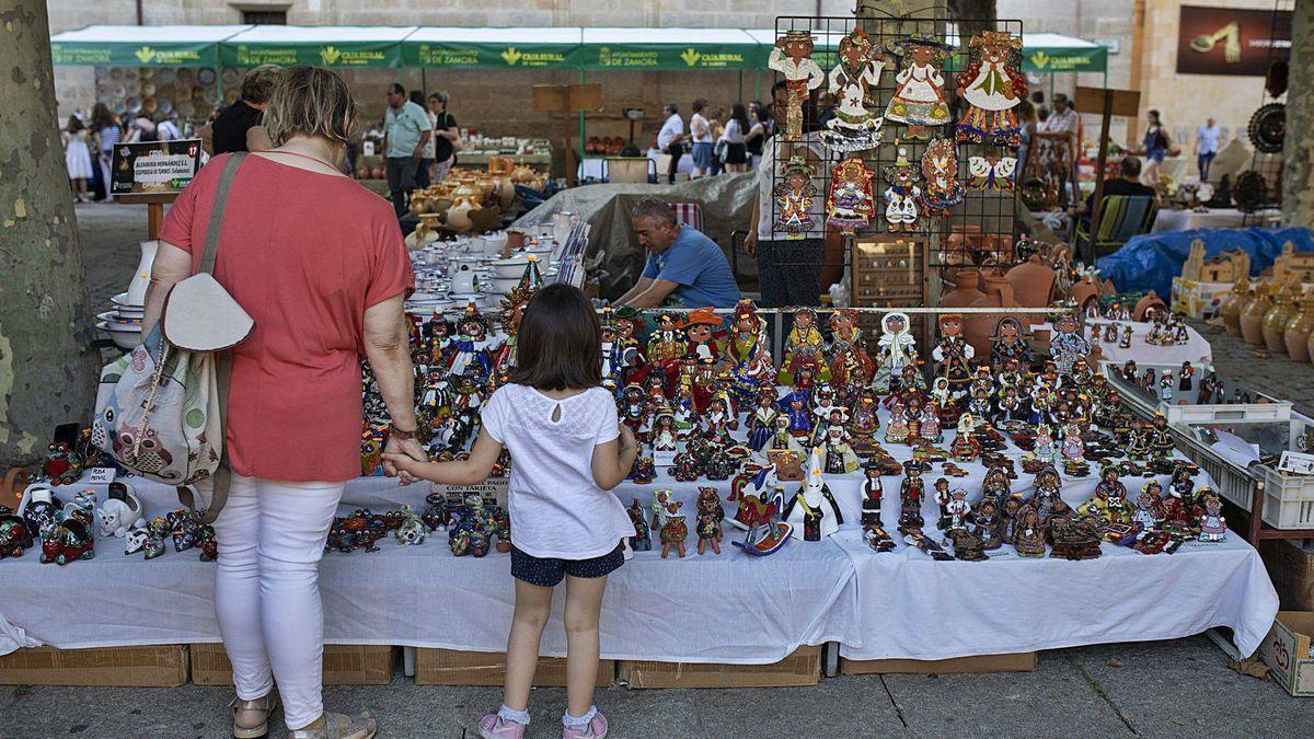 Una mujer y una niña observan uno de los puestos de la Feria de la Cerámica de Zamora.