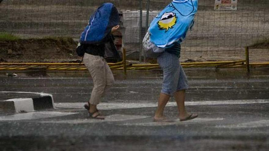 Dos personas se cubren con toallas por el aguacero, ayer, en Alicante