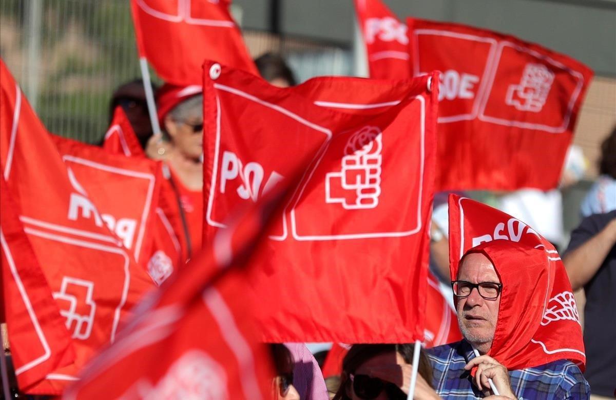 Un asistente al acto de cierre de campaña del PSOE en Madrid, se resguarda del sol con una bandera.