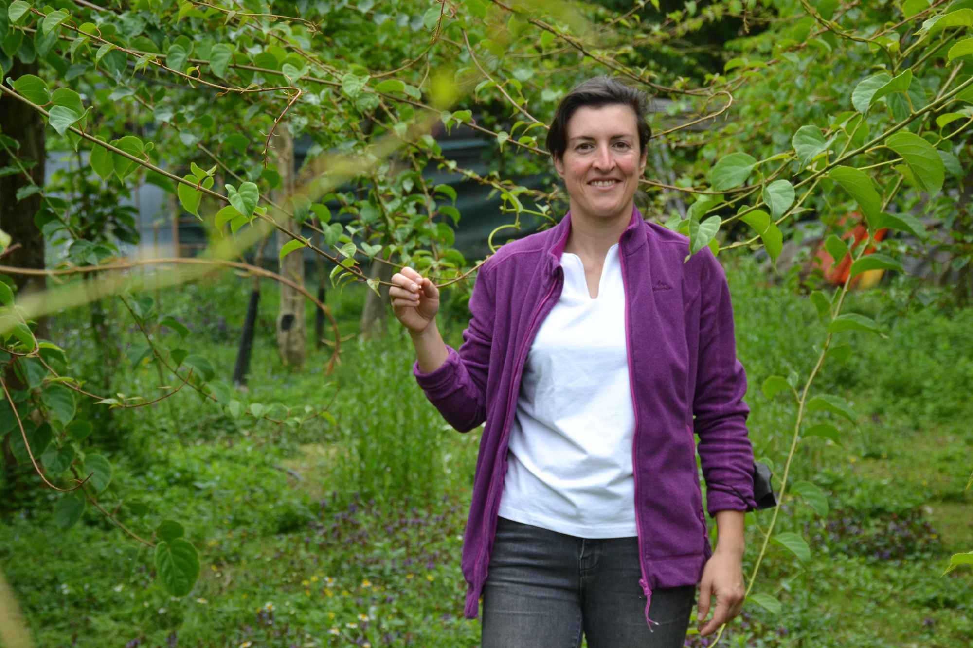 Primer plano de Cristina Secades en su finca junto a sus plantas de minikiwis.