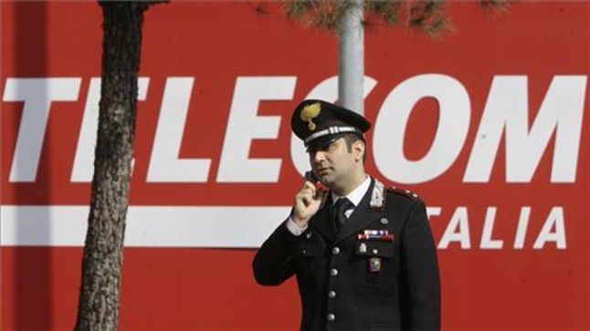 Un policía habla con su móvil frente a la sede de Telecom Italia en Rozzano.