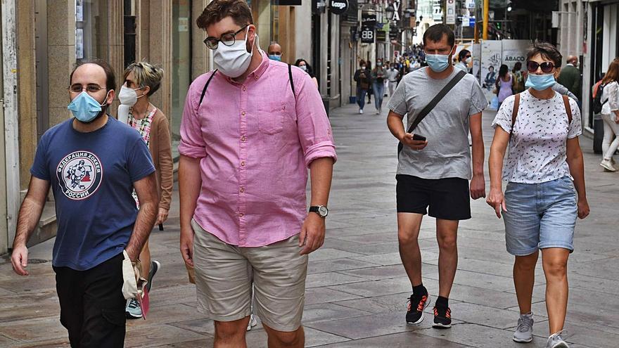 Ciudadanos con mascarillas pasean por la calle Real de A Coruña. |  // VÍCTOR ECHAVE