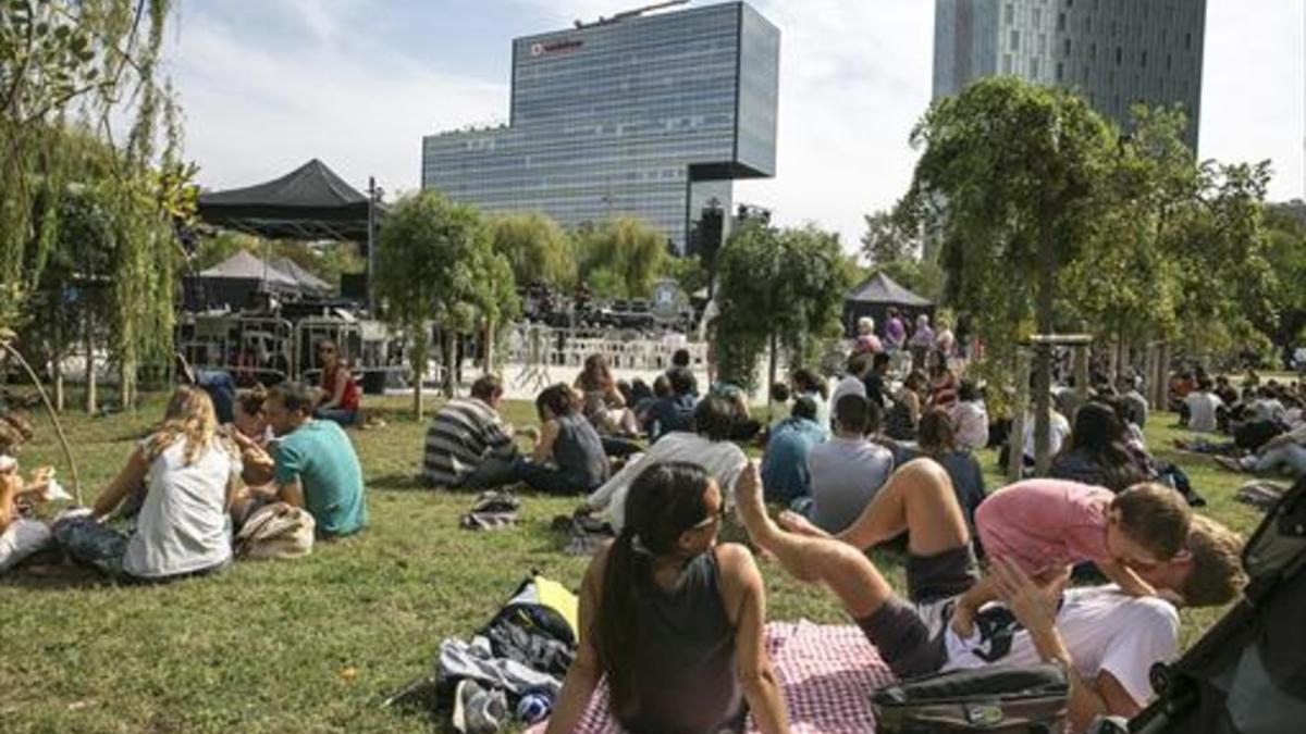 Familias sobre el césped del Parc del Centre de Poblenou, al mediodía.