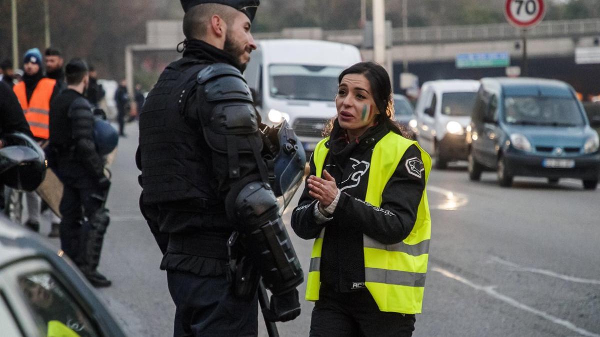 Una manifestante con el chaleco amarillo, símbolo de la protesta, habla con un policía, esta mañana en los alrededores de París.