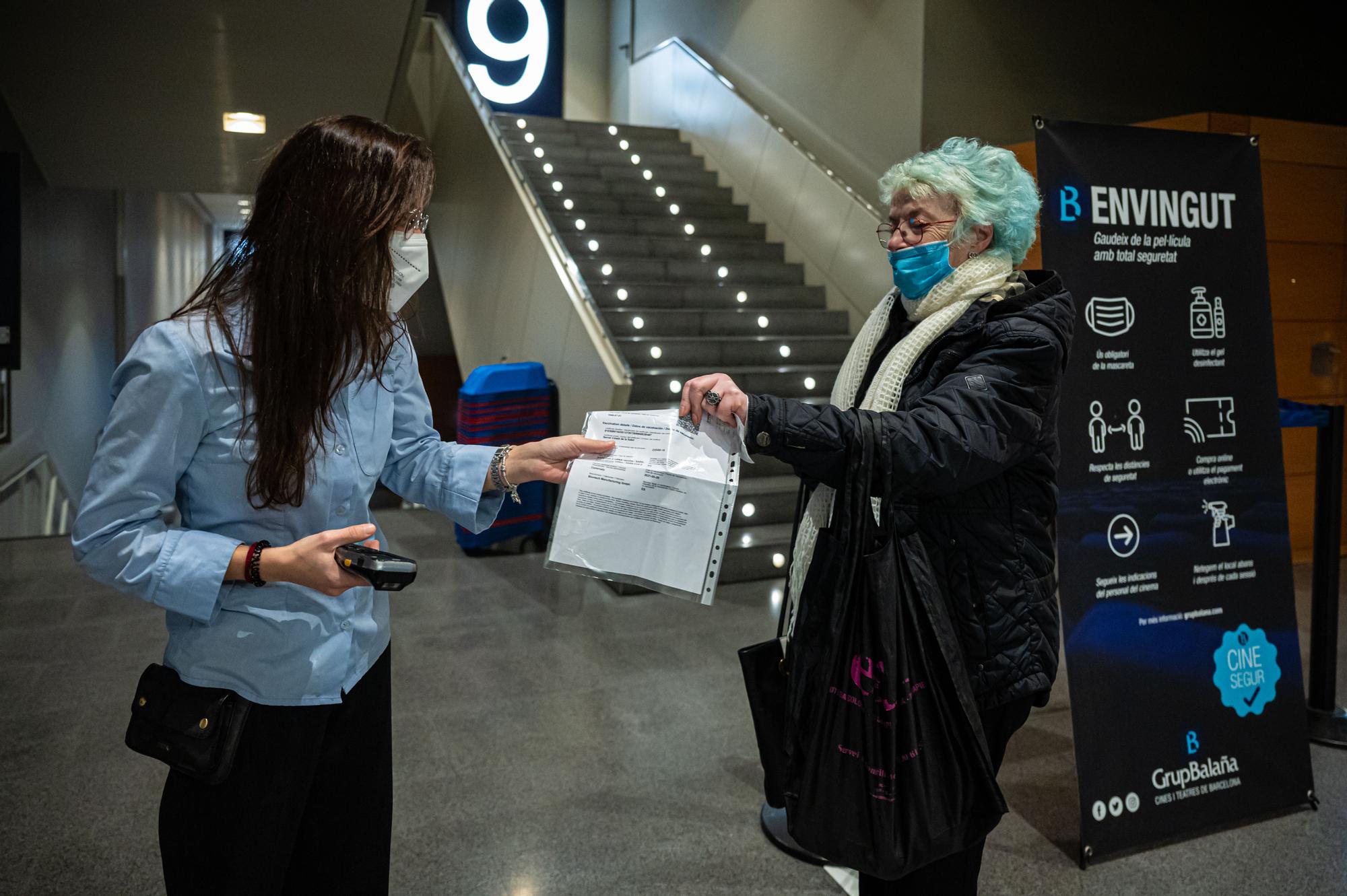 Una mujer muestra su pasaporte covid antes de entrar en el cine