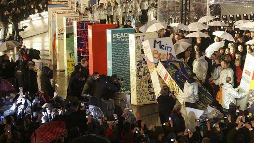 El público asistente a los actos del 20 aniversario de la caída del Muro empuja las últimas piezas del dominó que recorrió su trazado