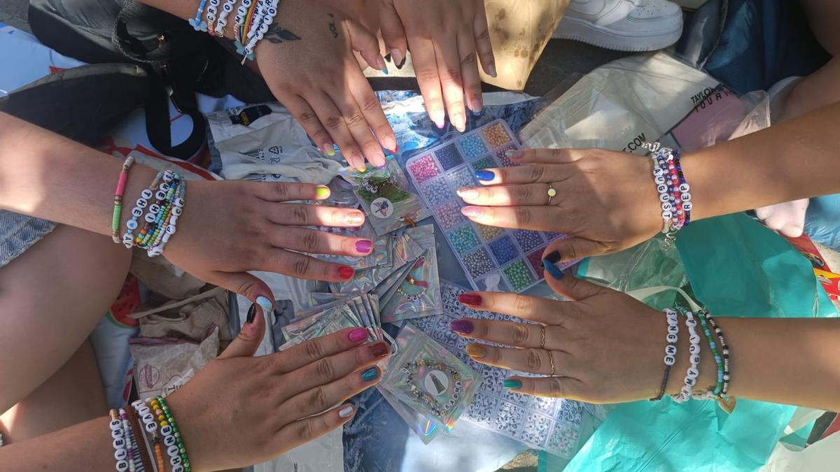 Varias 'swifties' muestran sus uñas decoradas con los colores de las Eras de Taylor Swift y sus brazos con pulseras de la amistad.
