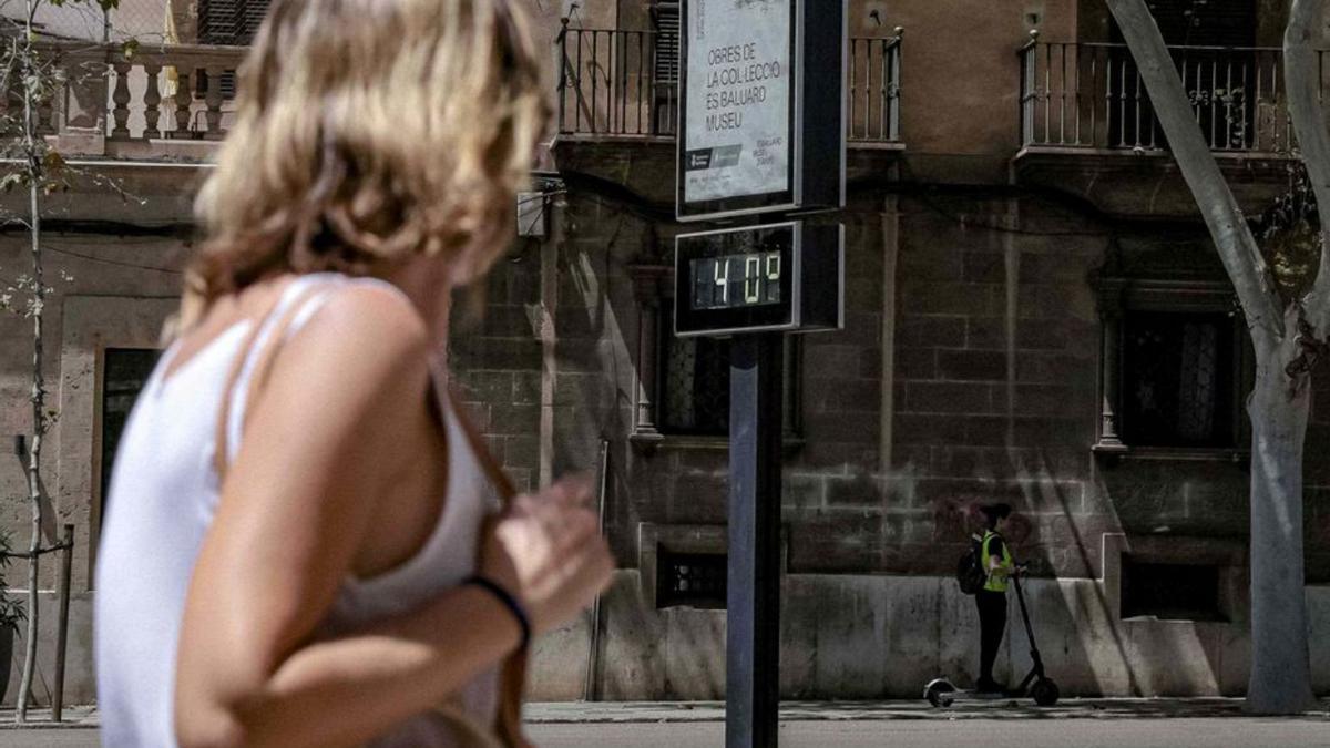 Una mujer pasa frente a un termómetro que marca 40 grados en Palma.
