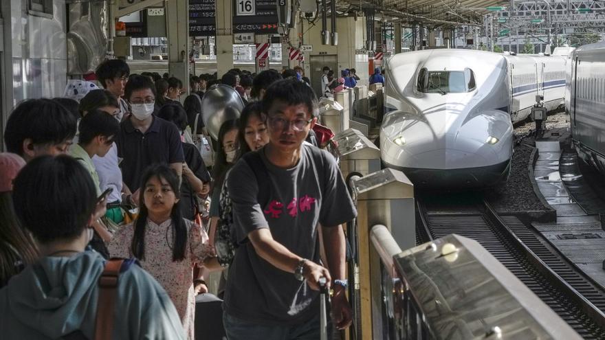 Pasajeros japoneses esperan la llegada del tren de alta velocidad.