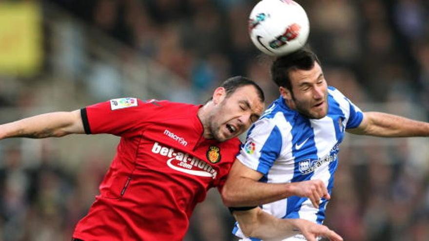 El delantero de la Real Sociedad Imanol Agirretxe (d) cabecea un balón ante el defensa del RCD Mallorca Iván Ramis.