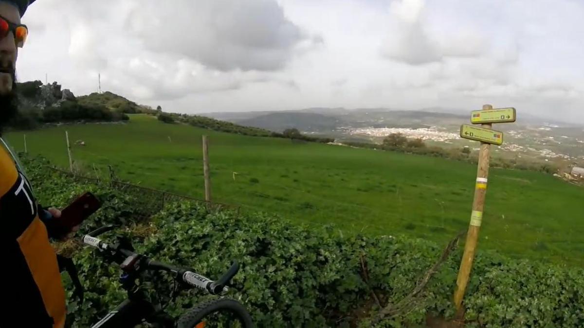 Un ciclista, en una de las varias rutas de la Sierra Norte de Málaga. Al fondo, Villanueva del Rosario.