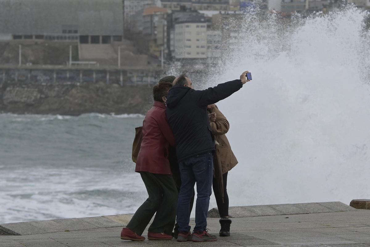 Un grupo de personas se hacen fotografías con las olas rompiendo en la zona de las Esclavas.