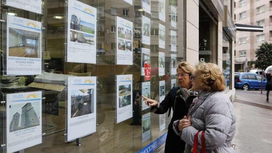 Dos mujeres ven los carteles de pisos en venta y en alquiler en una inmobiliaria.