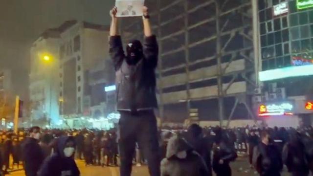 Imatge d’un vídeo en què apareix un manifestant emmascarat, en una de les protestes de Teheran, sosté una imatge del príncep hereu de l’Iran, Reza Pahlavi. | AP