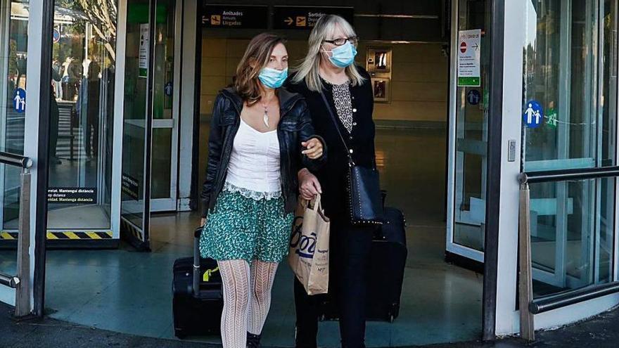 Dos mujeres con mascarilla salen de la terminal del aeropuerto de Ibiza.