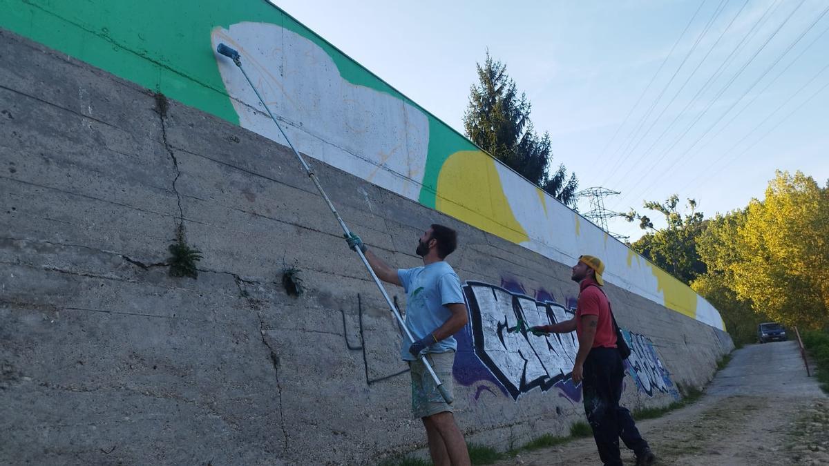 Iñaki García y Ángel Morgan pintan el mural artístico junto al río Sella, en Arriondas