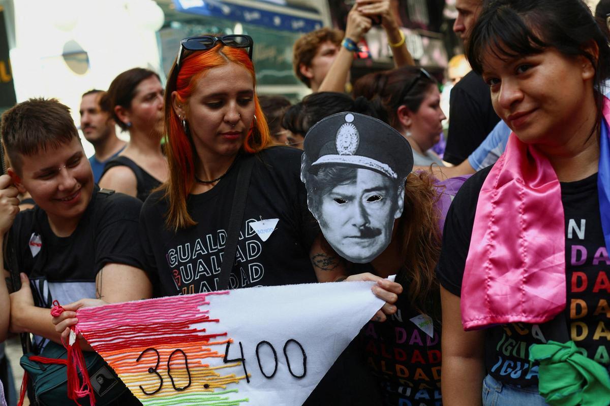 Un manifestante lleva una máscara con la mitad de la cara del presidente Milei y otra con el dictador Videla