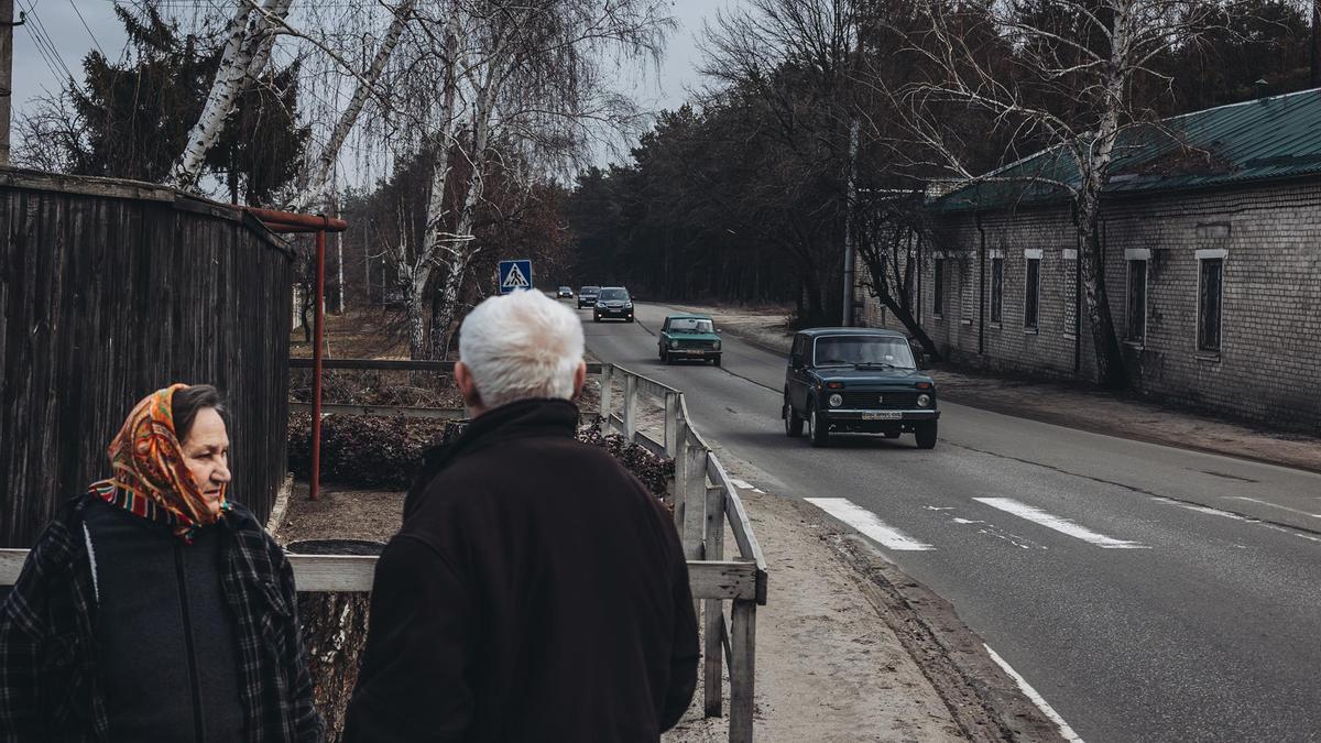 Unos civiles a las puertas de su casa observan la huida de cientos de vecinos en Lugansk.