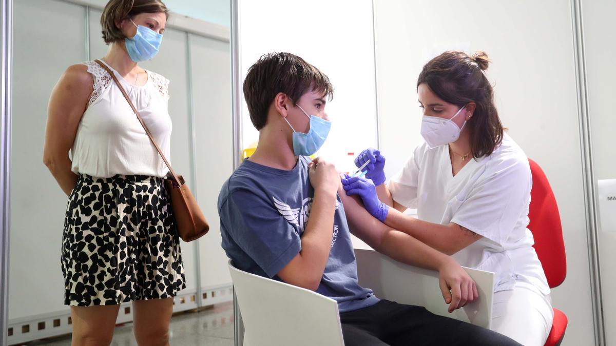 Sanitaria administrando la vacuna a un adolescente.