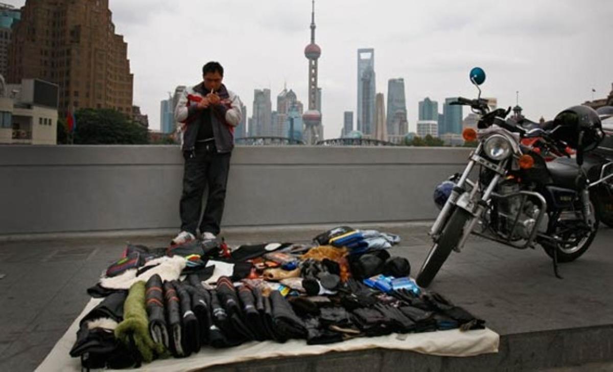 Un venedor ambulant fuma a prop dels seus productes d’hivern en una vorera davant del districte financer de Pudong a Xangai (Xina).