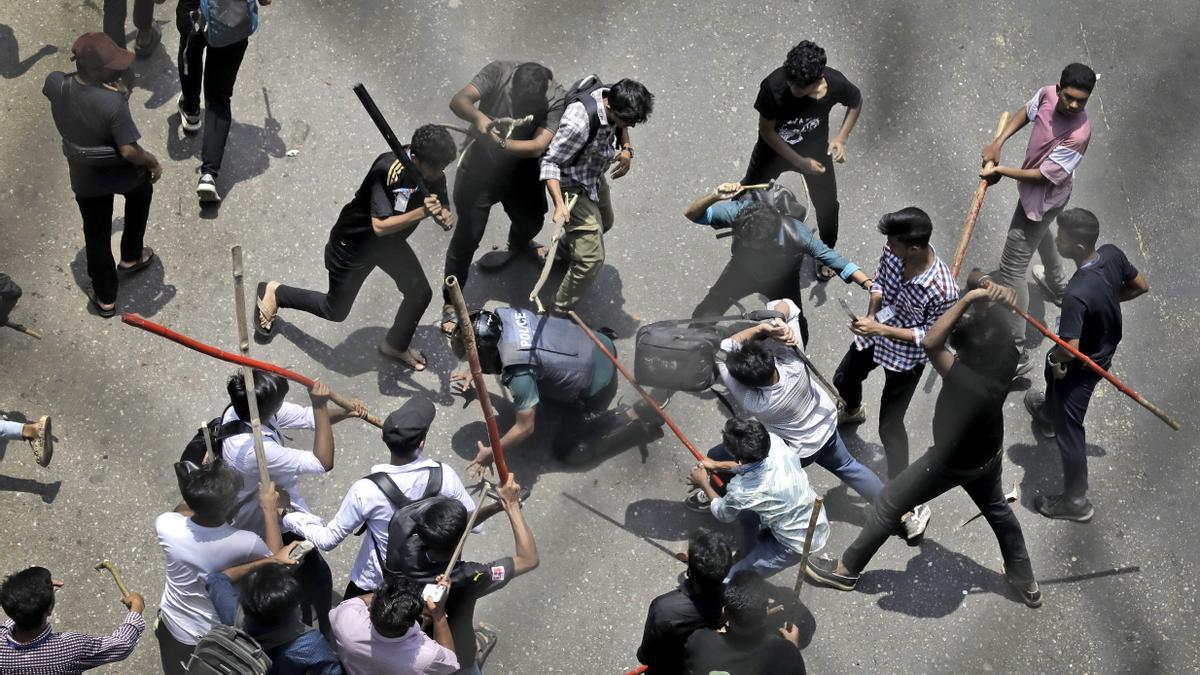 Varios estudiantes golpean a un policía con palos durante una protesta en Bangladesh, el 18 de julio.