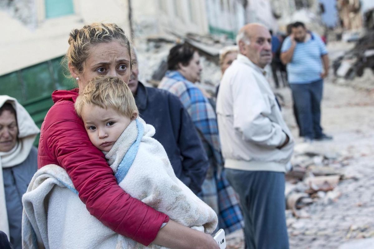 Una mujer abraza a su hijo en medio de los escombros en Amatrice.