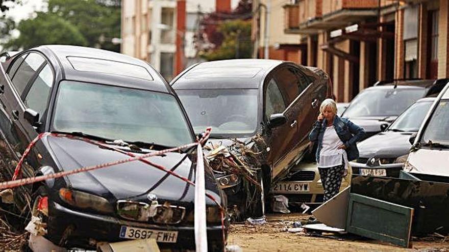 Una mujer habla por teléfono entre coches arrastrados por el agua en el centro de Tafalla.