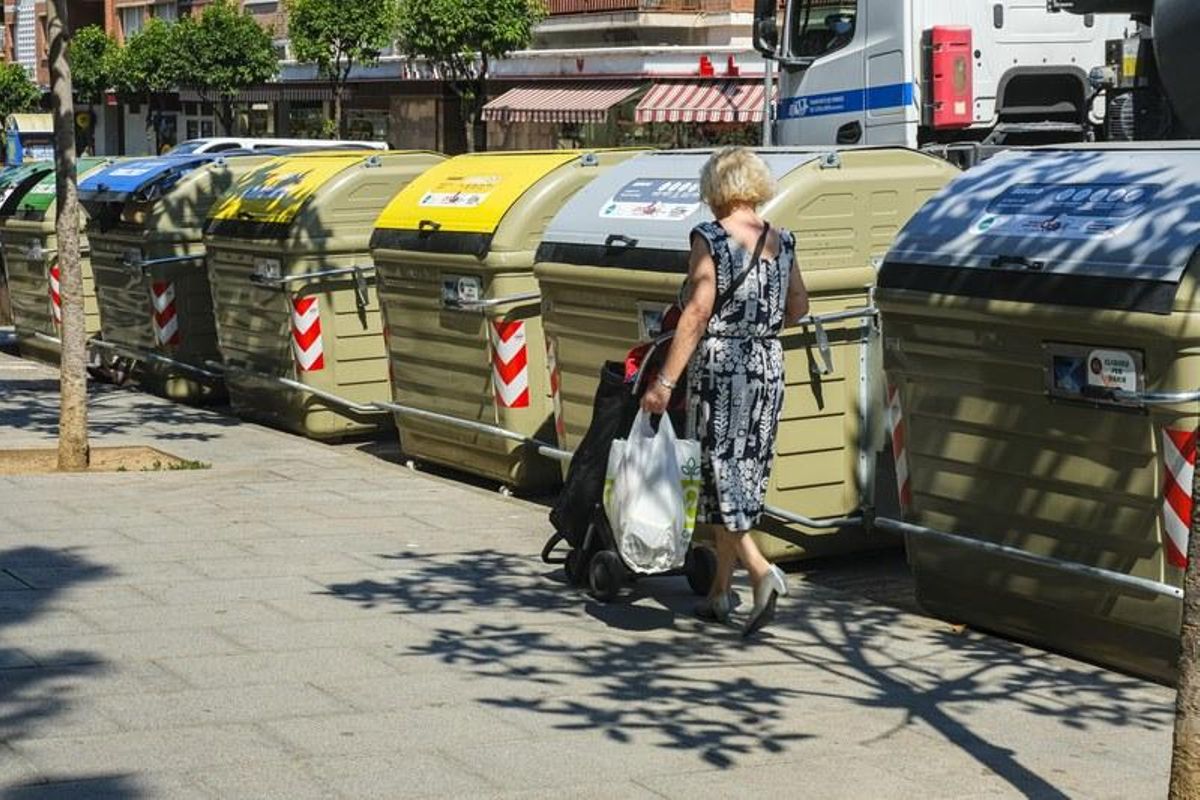 Una mujer se dispone a tirar la basura en una calle de Cornellà.