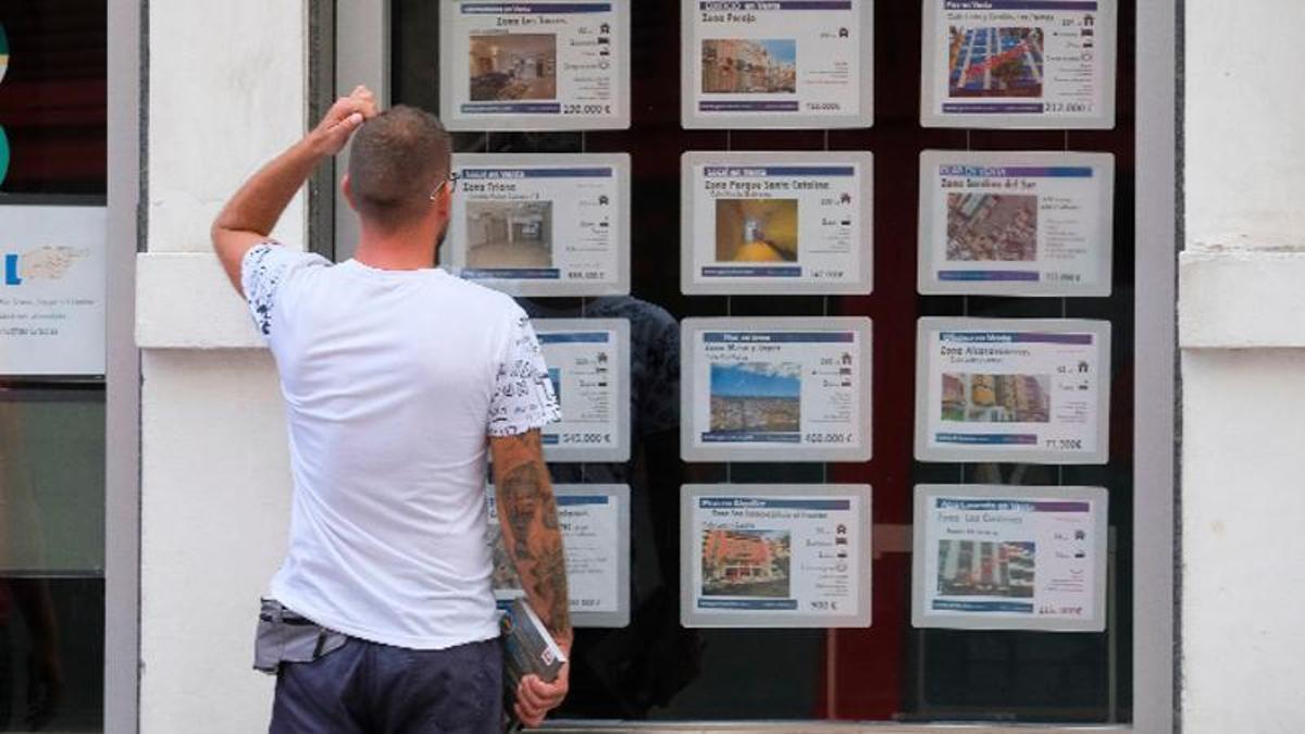 Un ciudadano observa las ofertas en el escaparate de una agencia inmobiliaria.