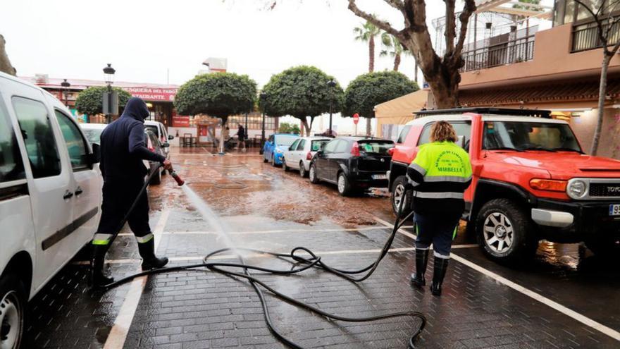 Dos operarios de Limpieza baldean una calle en Marbella.