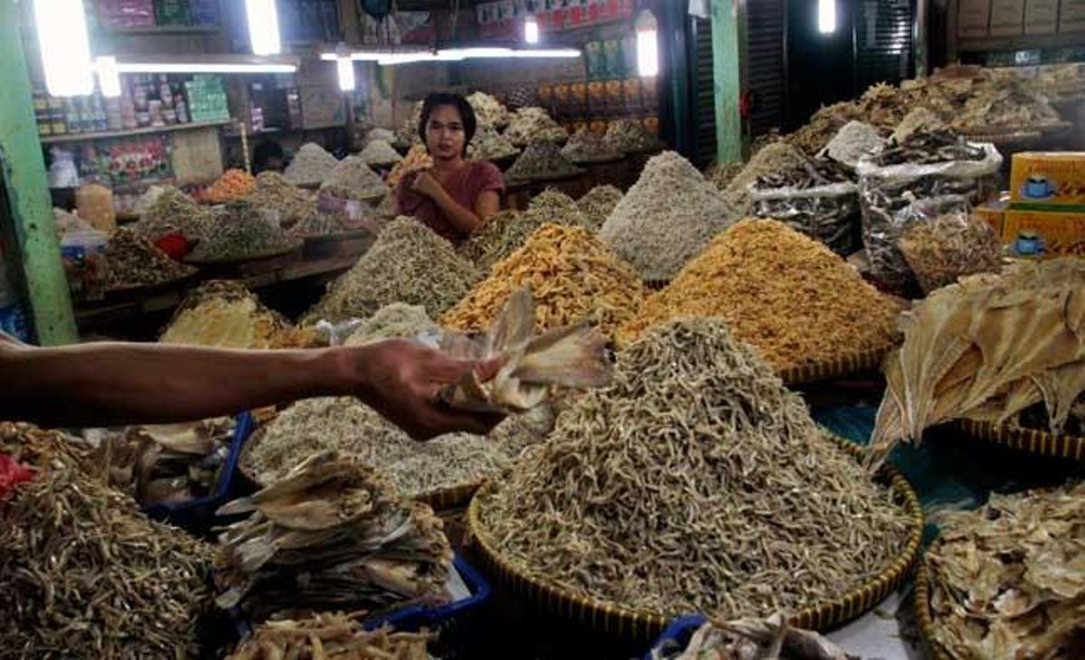 Una dona observa com un venedor ofereix peix salat en un mercat de Jakarta, Indonèsia.