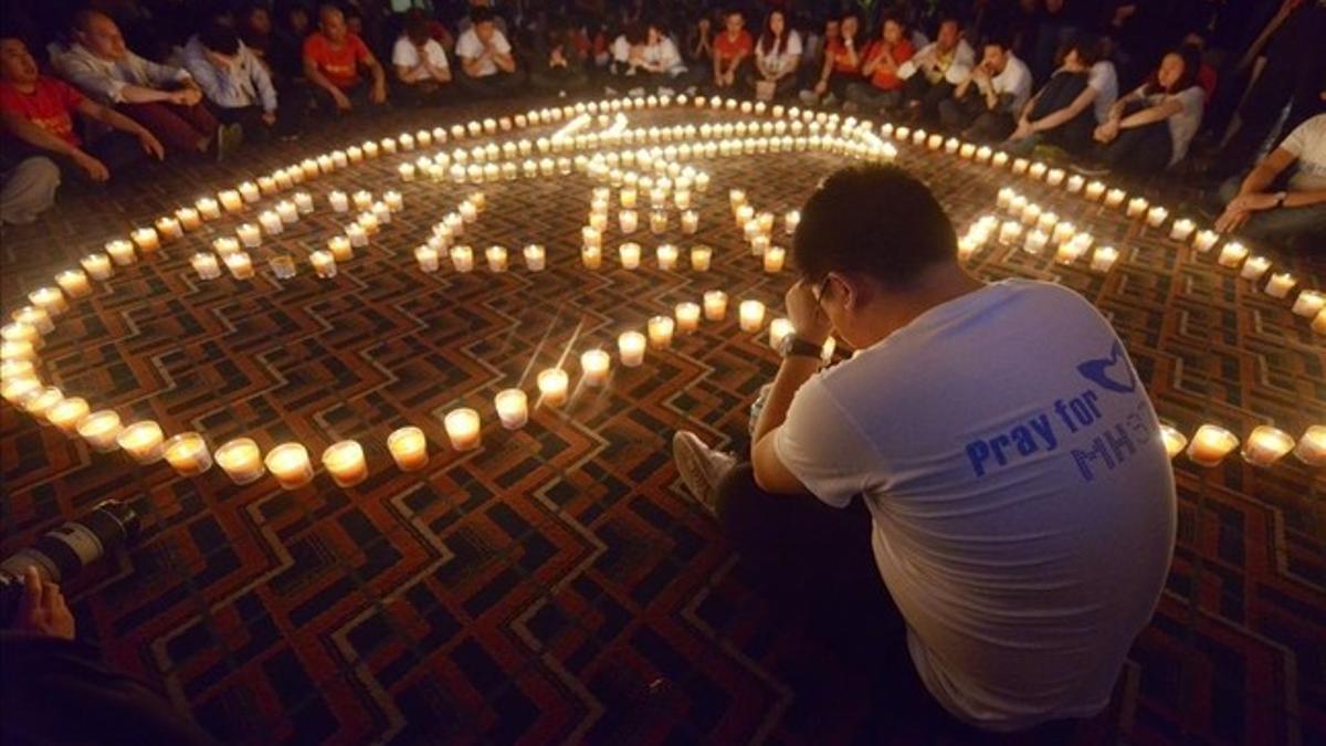 Familiares  de pasajeros del vuelo Malaysia Airlines MH370 rezan en el Metro Park Hotel en Pekin