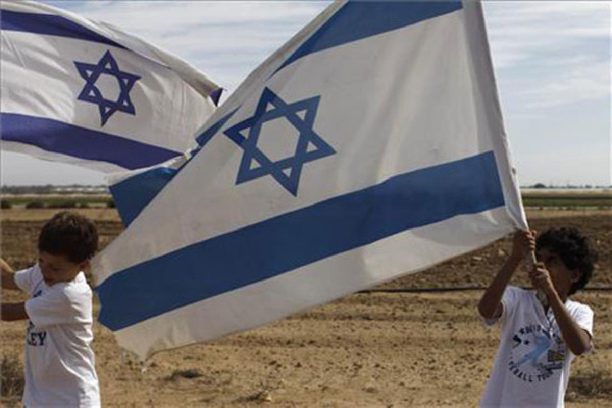 Dos nens fan onejar banderes israelianes mentre esperen l’arribada del soldat israelià capturat, Gilad Shalit, a prop de la cruïlla de Kerem Shalom, a la frontera amb la franja de Gaza.