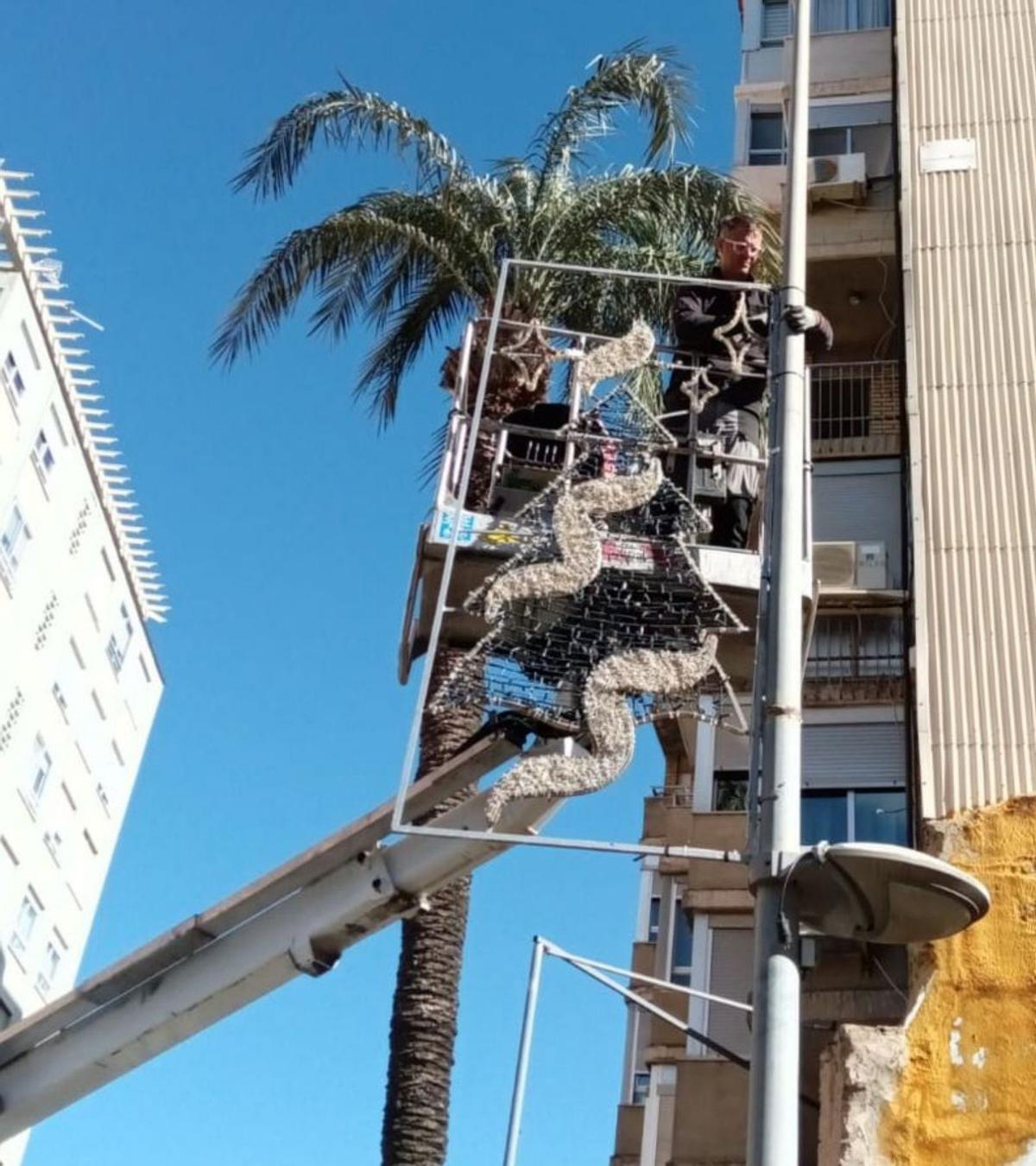 Un operario instala un elemento decorativo en una farola en Tavernes. A la derecha, ya colocada. | LEVANTE-EMV