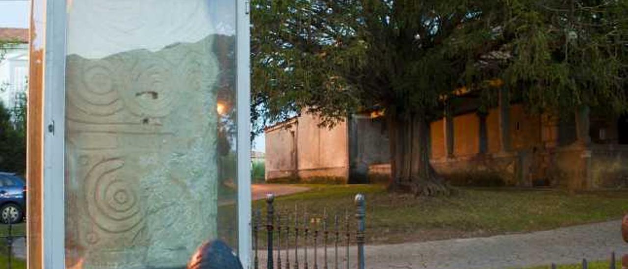 La estela funeraria de Duesos, en Caravia, con la sierra del Sueve reflejada en la vitrina.