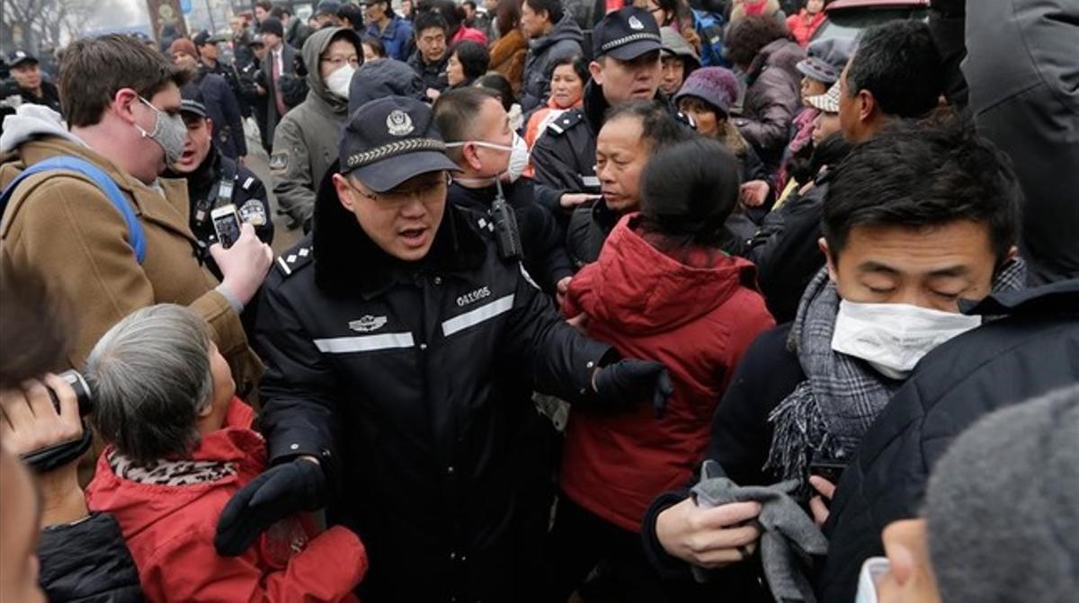 Un oficial de policía empuja a los manifestantes congregados frente al tribunal en el que era juzgado Pu Zhiqiang.