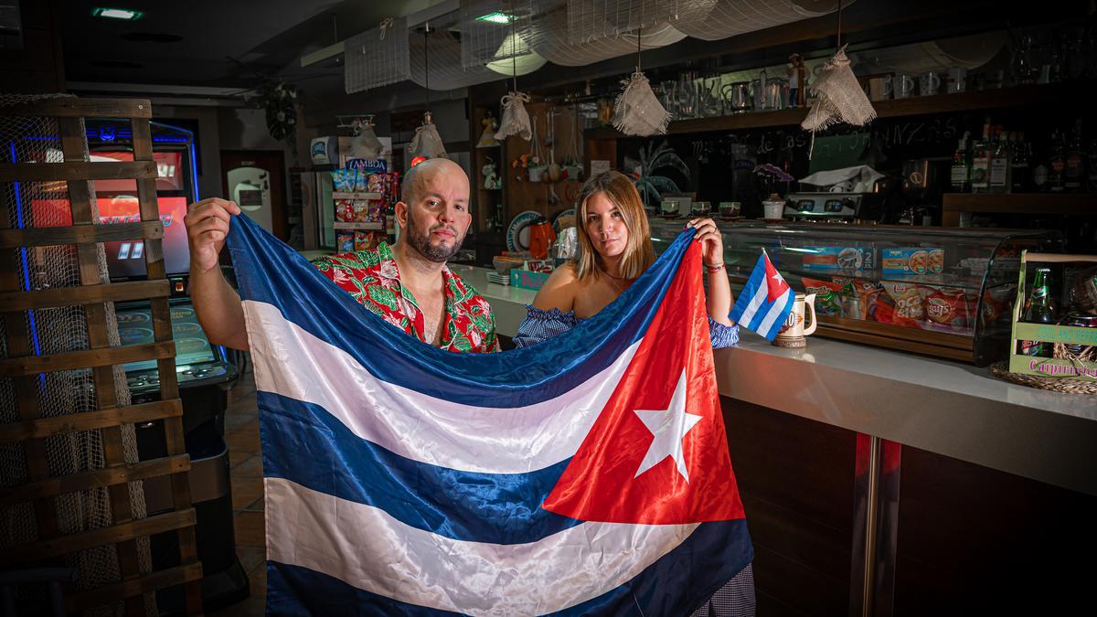 Riki y su hermana María posan con la bandera en el restaurante familiar.