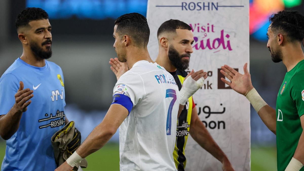 Cristiano Ronaldo y  Karim Benzema se cruzan antes del partido de fútbol de la Saudi Pro League entre Al-Ittihad y Al-Nassr en el estadio King Abdullah Sports City de Jeddah