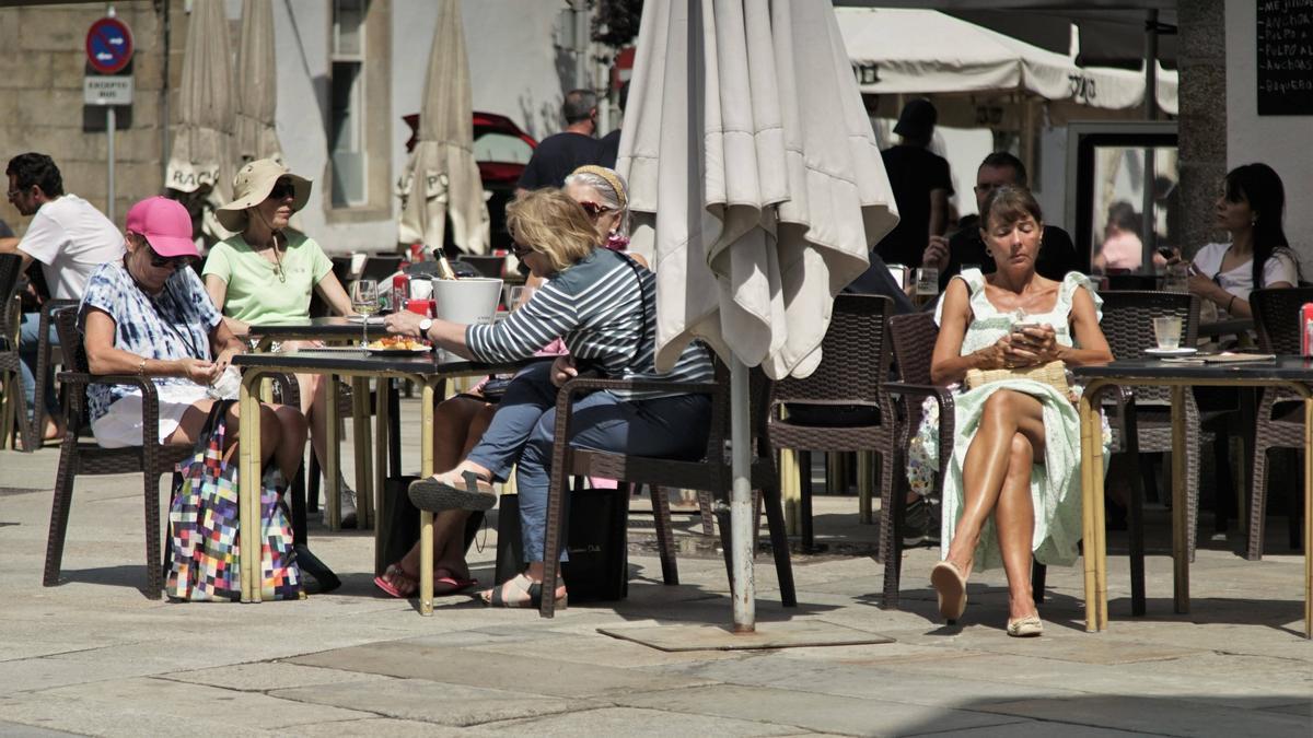 Turistas nunha terraza da praza de Mazarelos, en Santiago