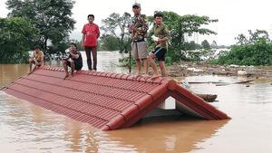 Un grupo de personas aguarda en lo alto de un tejado en una zona inundada en Laos.