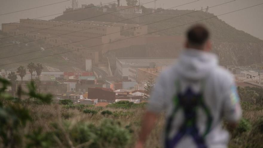 Un hombre camina con la baja visibilidad de la calima.