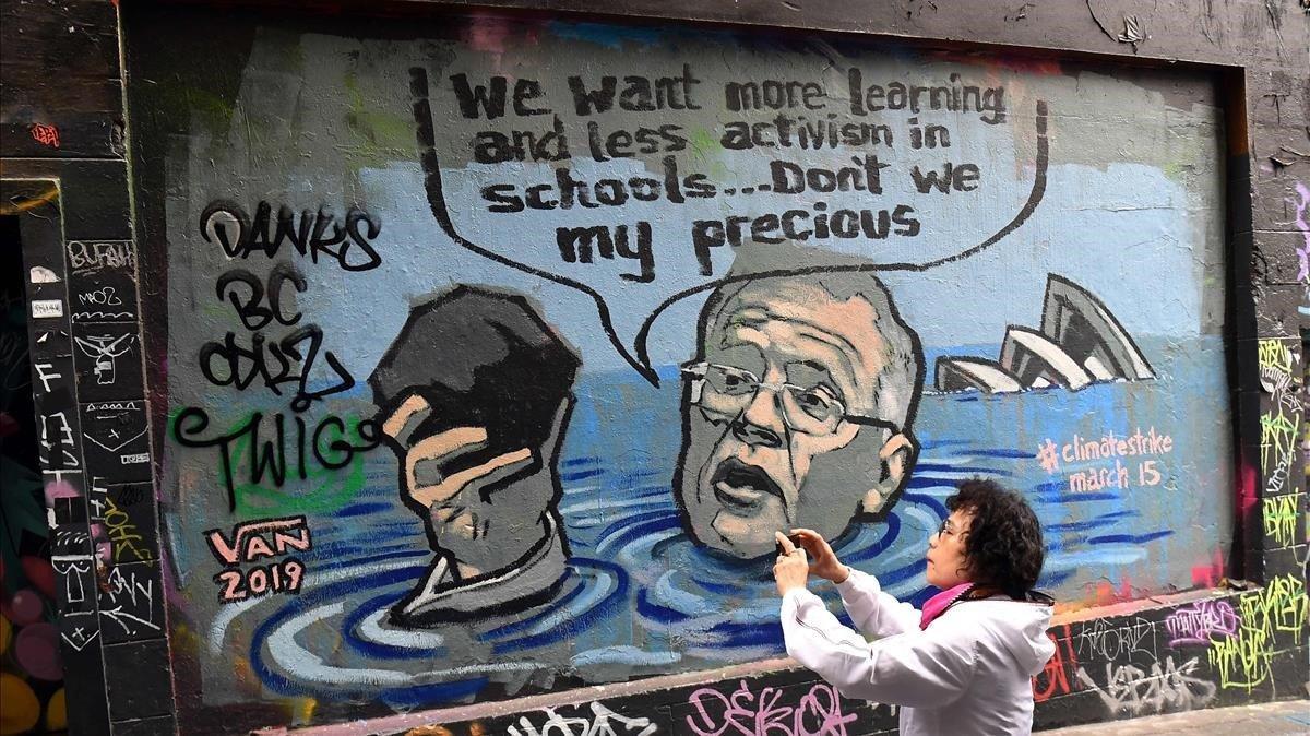 Una turista fotografia un mural donde se invita a la huelga escolar contra el cambio climaàtico.