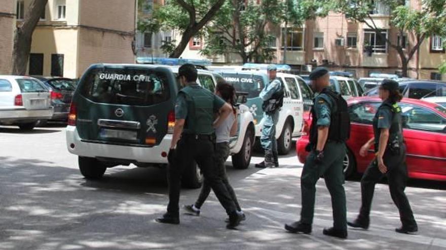 Agentes de la Guardia Civil trasladan a una de las detenidas durante uno de los registros.